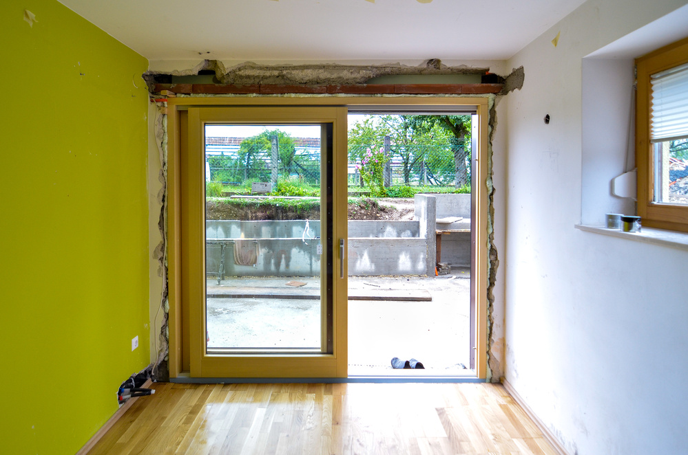 Replacing brick wall with glass sliding door in residential house. Construction renovation or remodelling project of inserting glass wall and new construction installations. View of outside terrace.