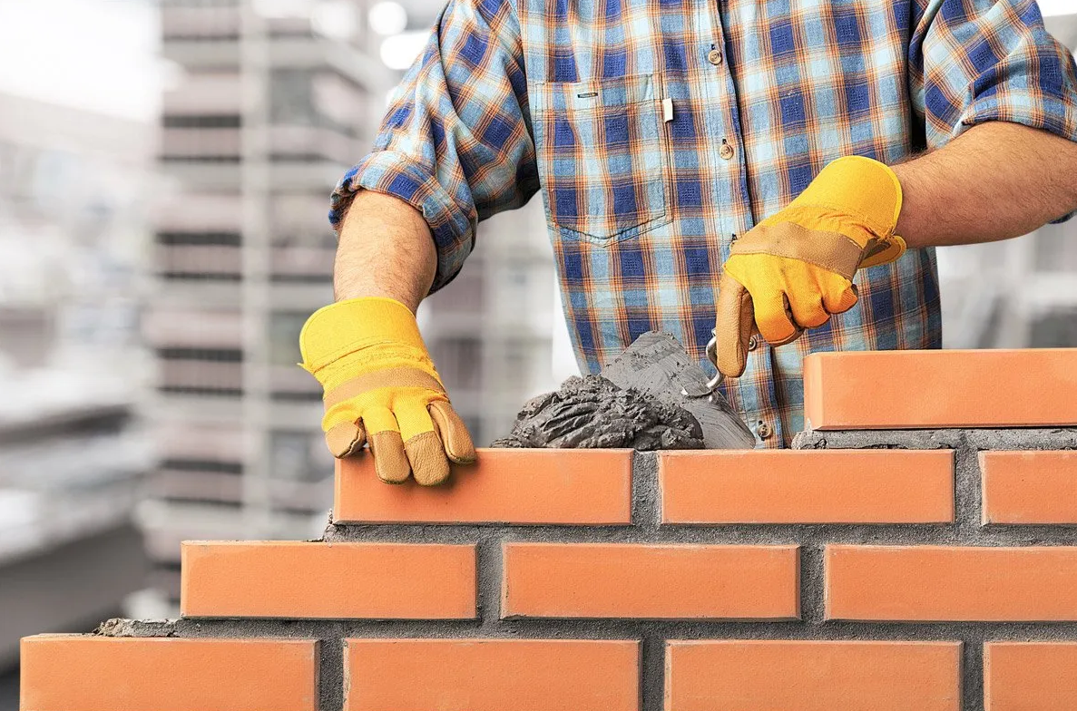 Man wearing gloves performing residential brick masonry work on new home build