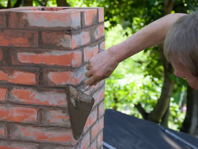 Man completing Masonry work around chimney on roof