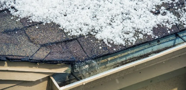 Snow on wore roof shingles with water draining in gutter